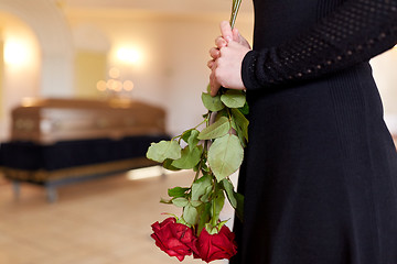 Image showing close up of woman with roses and coffin at funeral