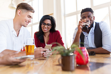 Image showing happy friends with smartphone drinking beer at bar