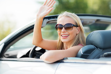 Image showing happy young woman in convertible car waving hand