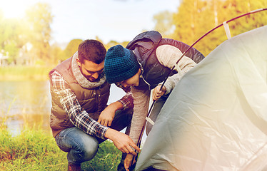 Image showing happy father and son setting up tent outdoors