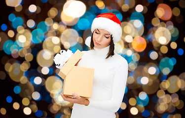 Image showing displeased woman in santa hat with christmas gift