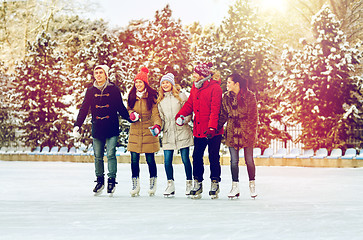 Image showing happy friends ice skating on rink outdoors