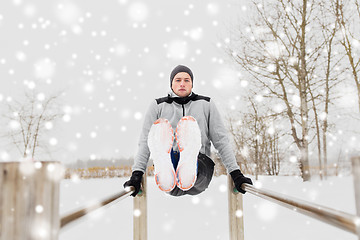 Image showing young man exercising on parallel bars in winter