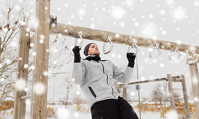 Image showing young man exercising on horizontal bar in winter