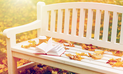 Image showing open book and coffee cup on bench in autumn park