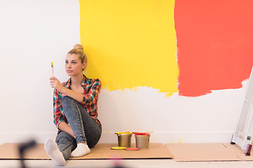 Image showing young female painter sitting on floor