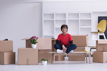 Image showing boy sitting on the table with cardboard boxes around him