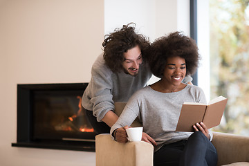 Image showing multiethnic couple hugging in front of fireplace