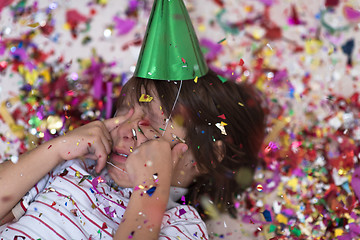 Image showing kid blowing confetti while lying on the floor