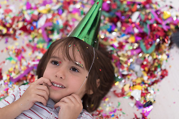 Image showing kid blowing confetti while lying on the floor