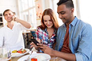 Image showing happy friends with smartphone at restaurant