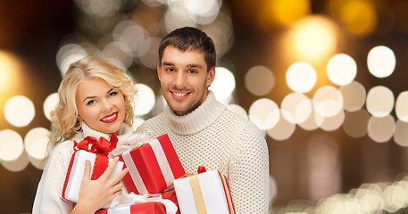 Image showing happy couple in sweaters holding christmas gifts