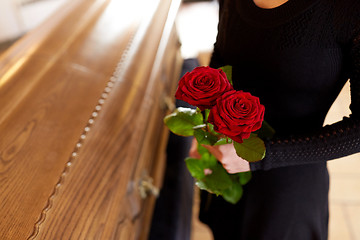 Image showing woman with red roses and coffin at funeral