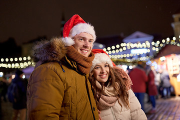 Image showing happy couple in santa hats at christmas market