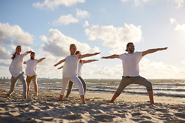 Image showing group of people making yoga exercises on beach