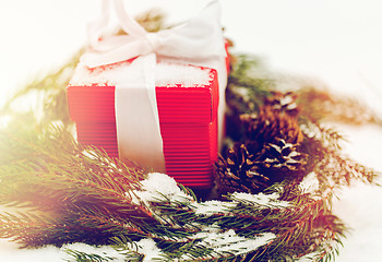 Image showing christmas gift and fir wreath with cones on snow