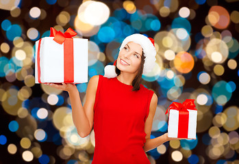 Image showing smiling woman in santa hat with christmas gifts