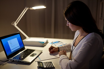 Image showing woman with calculator and papers at night office