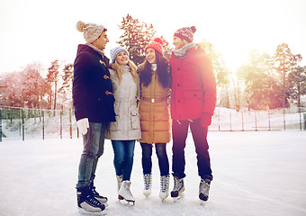 Image showing happy friends ice skating on rink outdoors