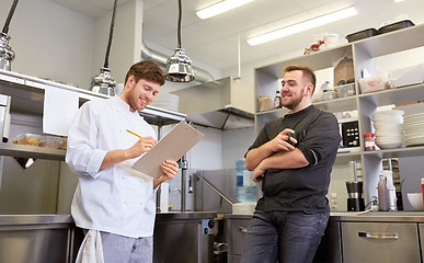 Image showing happy smiling chef and cook at restaurant kitchen