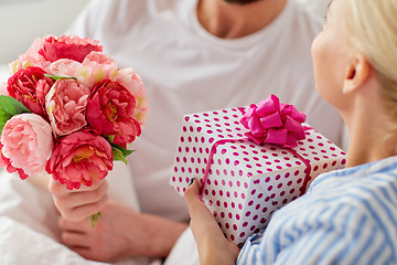 Image showing close up of couple with gift and flowers in bed