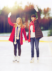 Image showing women or friends waving hands on skating rink