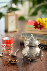 Image showing Dry tea leaves on spoon and teapot