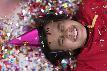 Image showing kid blowing confetti while lying on the floor