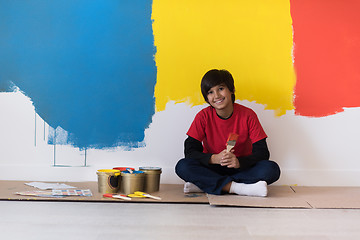 Image showing young boy painter resting after painting the wall