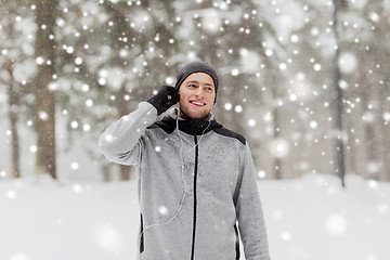 Image showing happy sports man with earphones in winter forest