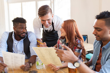 Image showing waiter and friends with menu and drinks at bar