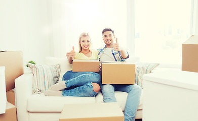 Image showing happy couple with boxes showing thumbs up at home