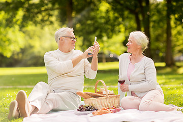 Image showing senior couple taking picture by smartphone at park
