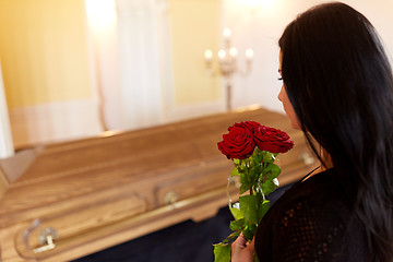 Image showing woman with red roses and coffin at funeral