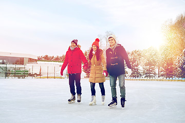 Image showing happy friends ice skating on rink outdoors