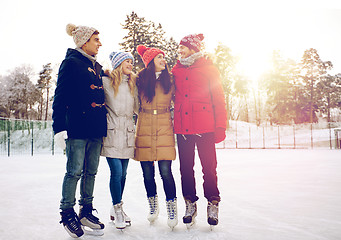 Image showing happy friends ice skating on rink outdoors