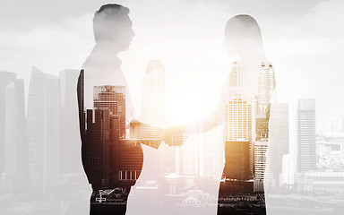 Image showing business people shaking hands over city background