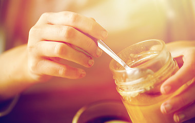 Image showing close up of woman hands with honey jar and spoon