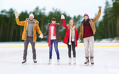 Image showing happy friends waving hands on outdoor skating rink