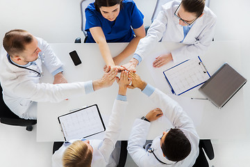 Image showing group of doctors making high five at table