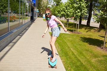 Image showing happy teenage girl in shades riding on longboard