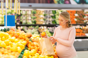 Image showing pregnant woman with bag buying oranges at grocery