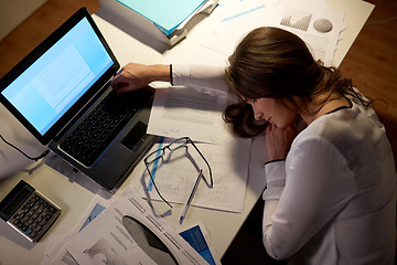 Image showing tired woman sleeping on office table at night