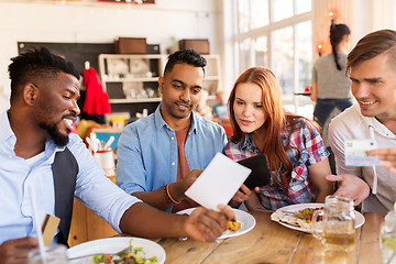 Image showing happy friends with money paying bill at restaurant