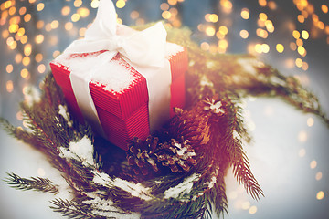 Image showing christmas gift and fir wreath with cones on snow