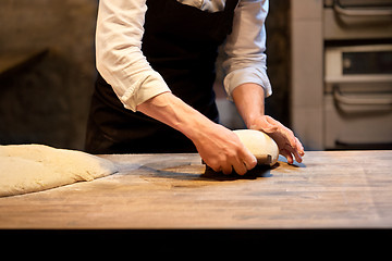 Image showing baker portioning dough with bench cutter at bakery