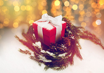 Image showing christmas gift and fir wreath with cones on snow