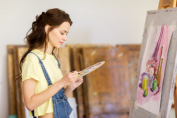 Image showing student girl with easel painting at art school