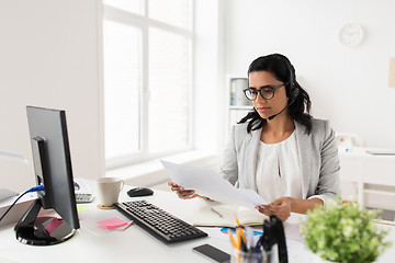 Image showing businesswoman with headset and papers at office