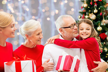 Image showing happy family with christmas gifts over lights